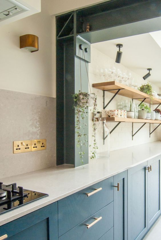 a navy one wall kitchen with a white subway tile backsplash and countertops, open blonde wood shelves and greenery