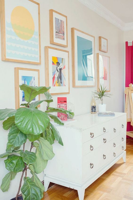 a pretty colorful gallery wall with matching light stained frames and bold and pastel shades is amazing