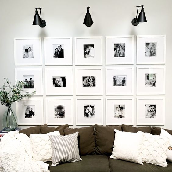 a pretty gallery wall with white frame sand matting and small black and white family pics accented with sconces