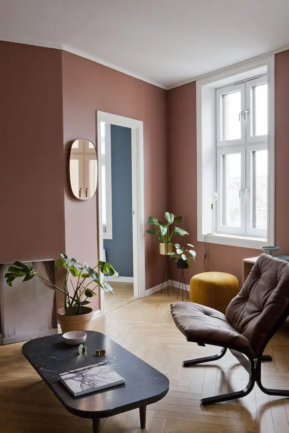 a pretty mauve living room with chic and refined furniture, potted greenery and a chic mirror is a very stylish space