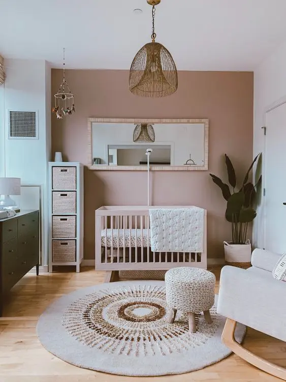 a pretty nursery with a mauve accent wall, stylish mid-century modern furniture, pendant lamps and a statement plant