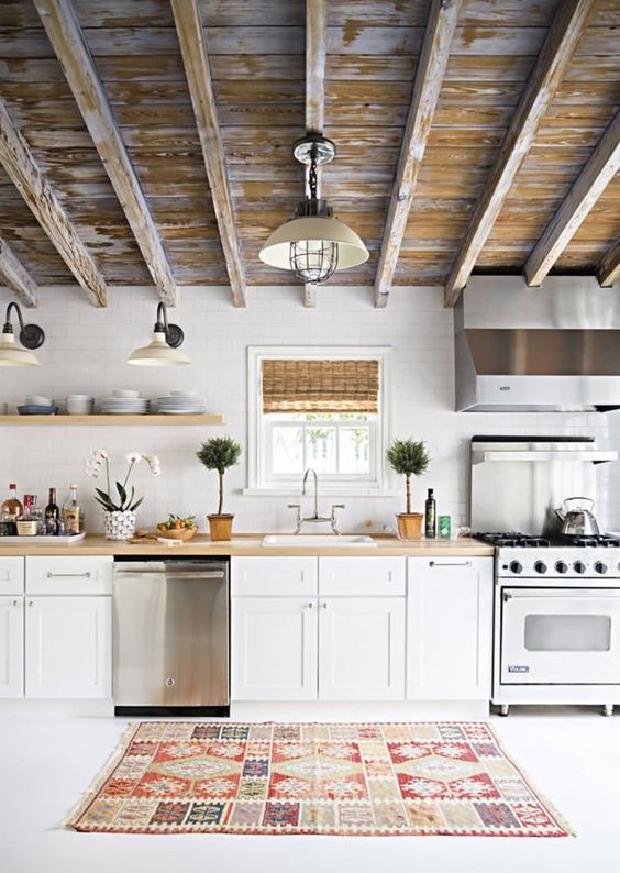 a pretty one wall kitchen with white cabinets, butcherblock countertops and a shabby chic ceiling is very welcoming