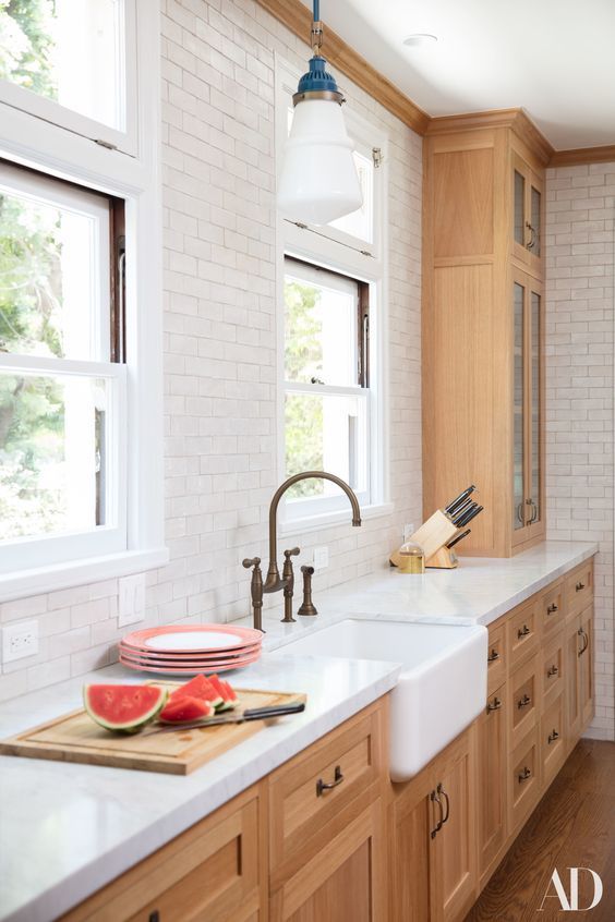 a pretty stained kitchen with white butcherblock countertops, a white subway tile backsplash and lovely retro pendant lamps