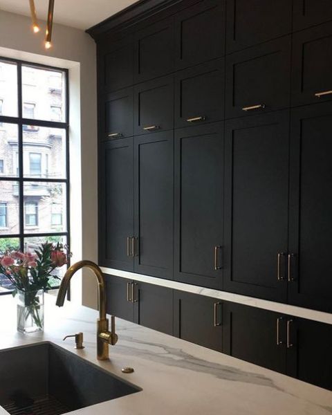 a refined black shaker style kitchen with white quartz countertops, brass and gold touches is a very stylish and elegant space