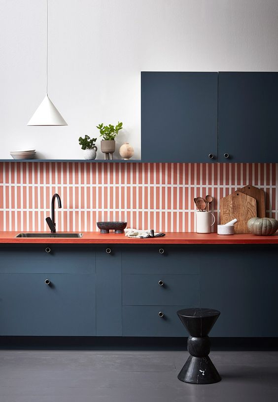 a refined navy one wall kitchen with an orange skinny tile backsplash plus an orange countertop and a white pendant lamp