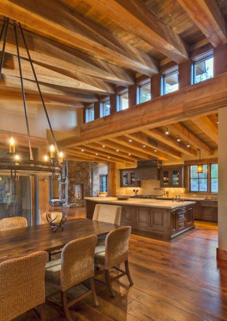 a rustic space with a slanted wooden ceiling with beams, heavy wooden furniture and lights plus clerestory windows for more light inside