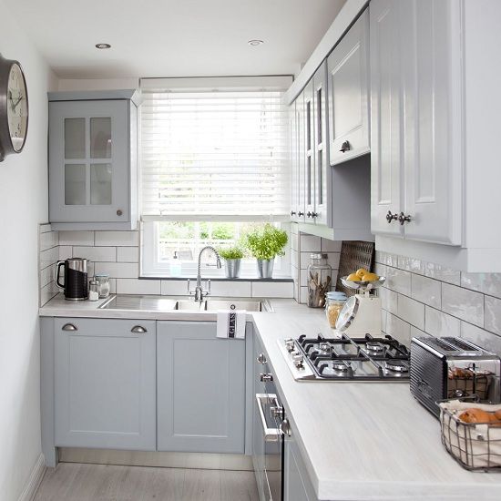 A small grey L shaped kitchen with a white tile backsplash and white stone countertops is a pretty and welcoming space