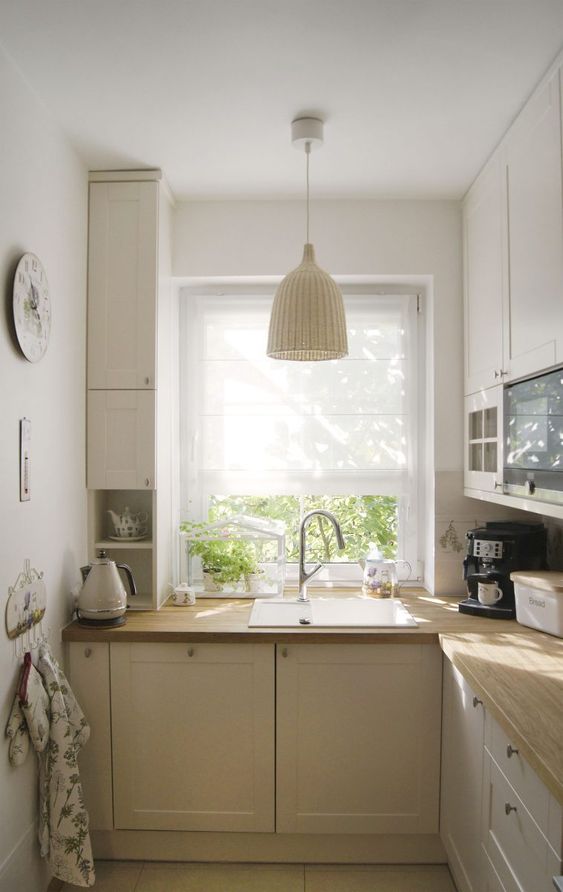a small neutral farmhouse kitchen with light butcherblock countertops and woven lamps and natural light