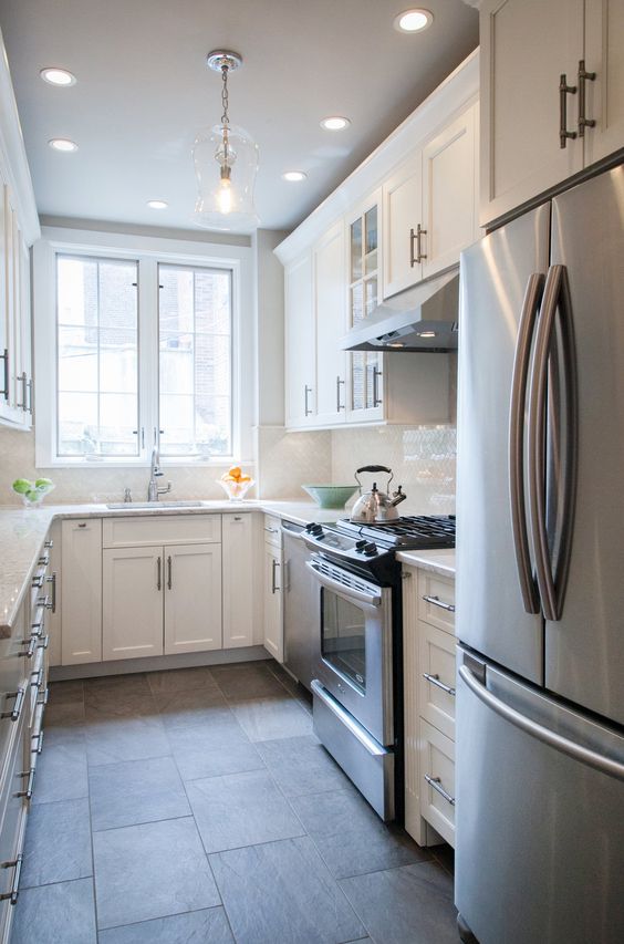 A small white U shaped kitchen with a white tile backsplash and white countertops is a very welcoming space