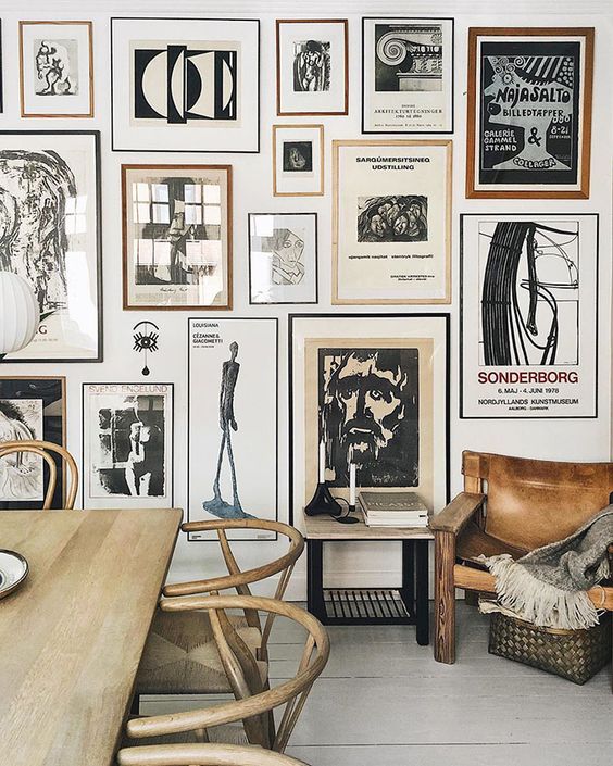 A stunning gallery wall with thin black and brown frames and black and white artworks is a bold eye catcher