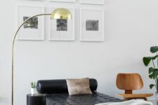 a stylish and polished nook with a grid gallery wall, a black leather daybed, a chair and a side table, a chic floor lamp