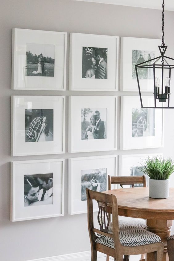 a stylish gallery wall with black and white photos in matching white frames is a preppy idea with chic