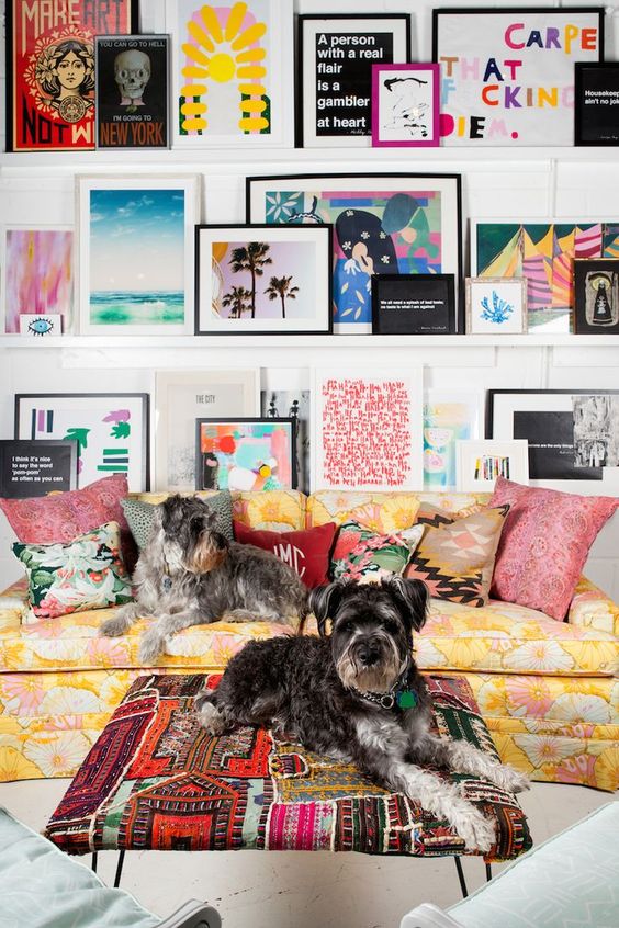 a super bright gallery wall with various kinds of art and posters in mismatching frames placed on white ledges is chic