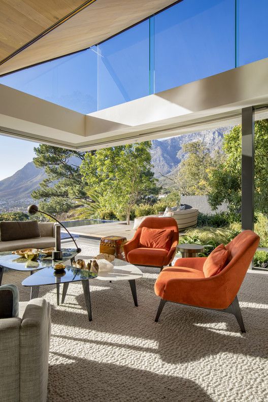 a super chic mid-century modern living room with glazed walls and clerestory windows, with cool seating furniture and wonderful views