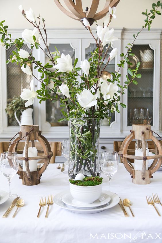 a tall clear vase with greenery and white blooms is a very fresh and beautiful spring centerpiece to rock