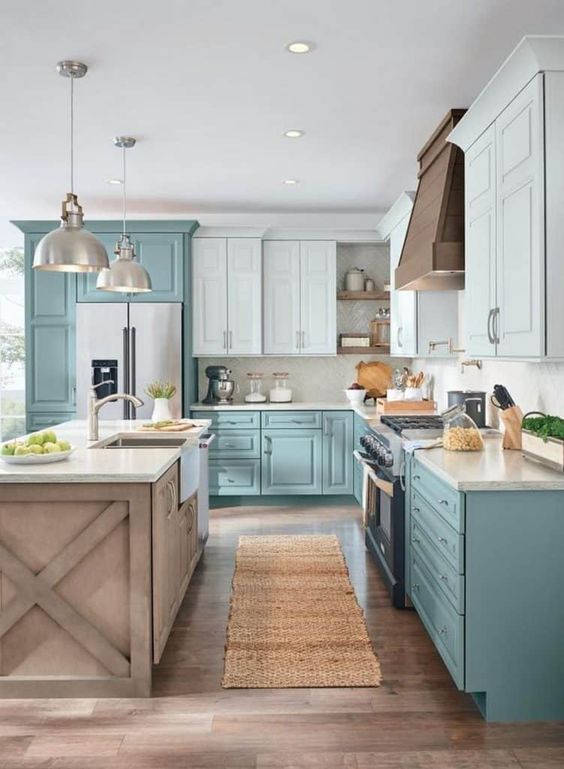 A two tone L shaped kitchen in turquoise and light blue, with a wooden kitchen island and pendant lamps