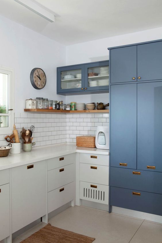 a two-tone L-shaped kitchen with copper handles and a white subway tile backsplash and a window