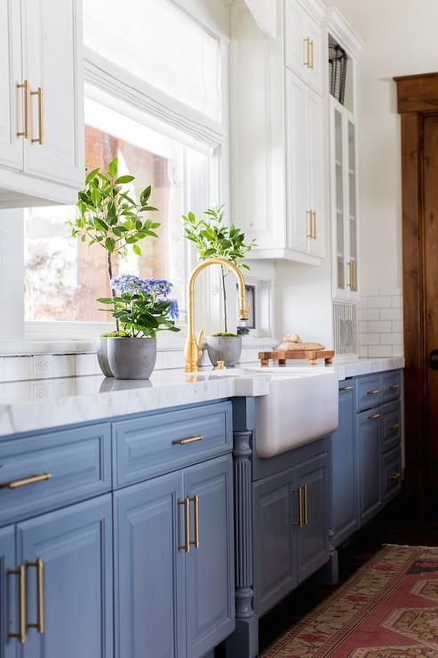a vintage blue and white one wall kitchen with a white stone countertops and a white tile backsplash plus gold touches