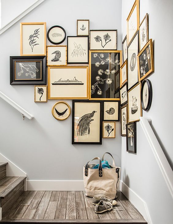 a vintage gallery wall with gold, black frames and vintage blakc and white artworks on vintage paper