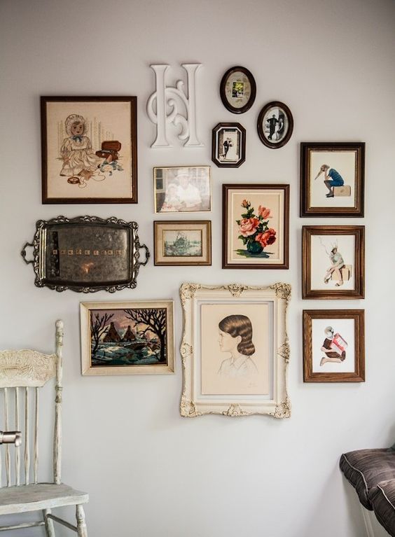 A vintage inspired gallery wall with elegant frames of various sizes and shapes, with a monogram and even a silver tray