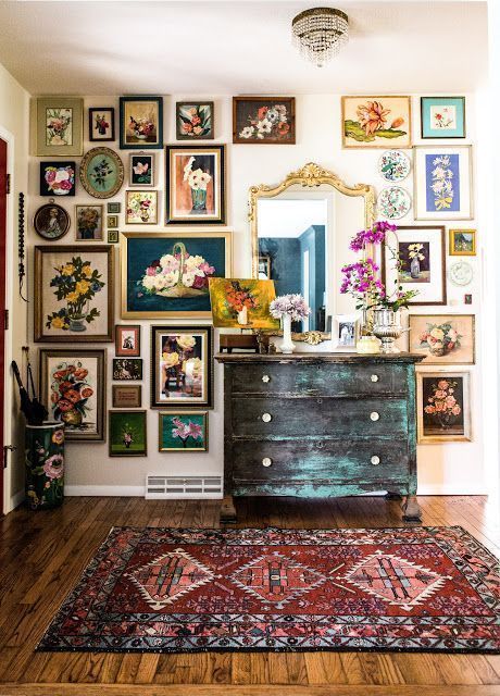a vintage style gallery wall with mismatching frames and lot sof colorful floral art for a refined and bright touch