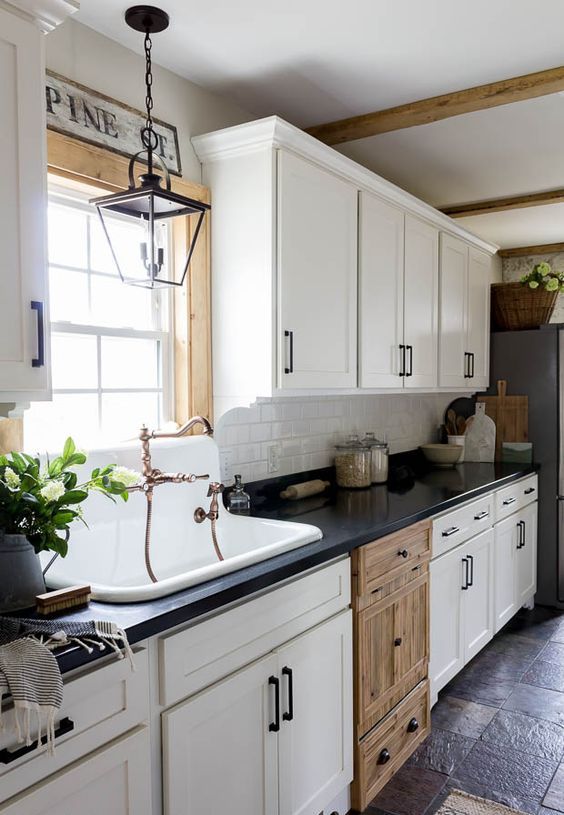 a vintage white one wall kitchen with a black coutnertop, a white subway tile backsplash and black fixtures is pure chic
