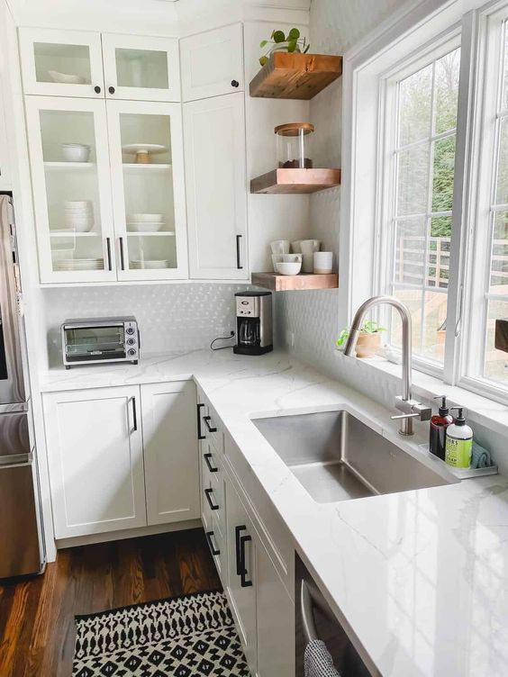 a white farmhouse L-shaped kitchen with white stone countertops, rich-stained wooden shelves