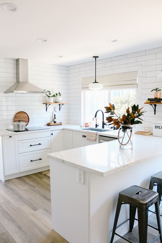 a white farmhouse U-shaped kitchen with a white subway tile backsplash and white stone countertops