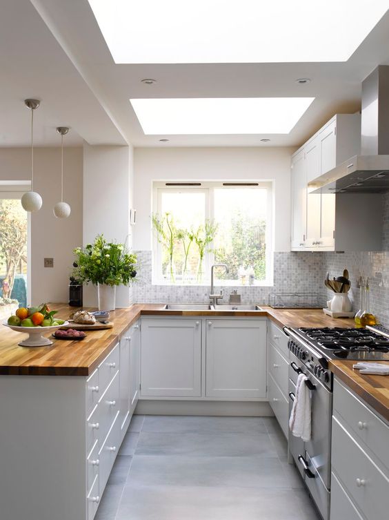 a white kitchen with butcherblock countertops, mosaic tiles and skylights is a very airy and welcoming space