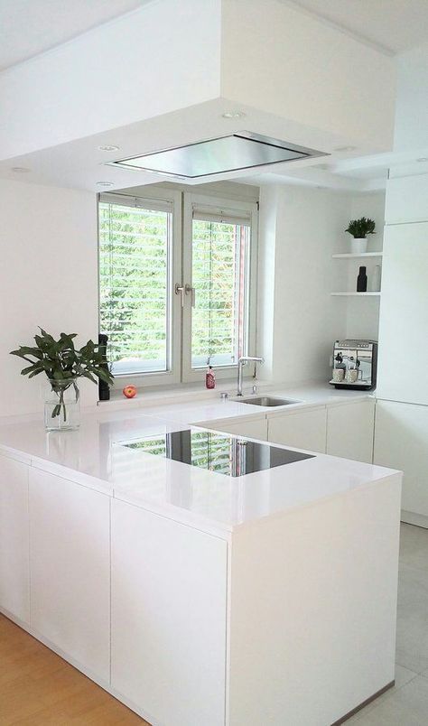 a white minimalist L-shaped kitchen with a matching hood and a window and a view is very airy and welcoming