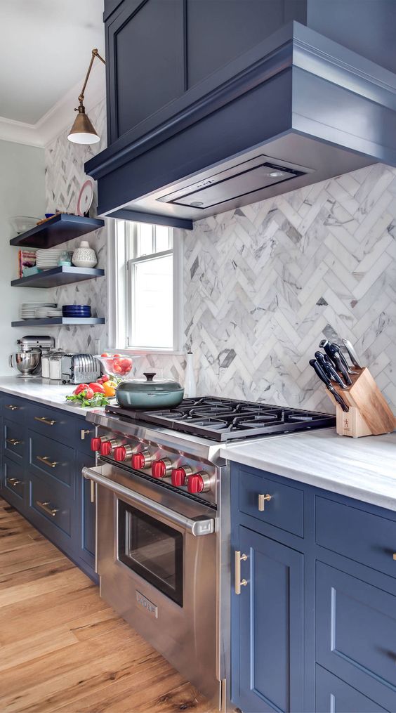 an amazing blue kitchen with shaker style cabinets, a white marble tile backsplash and white quartz countertops plus brass touches