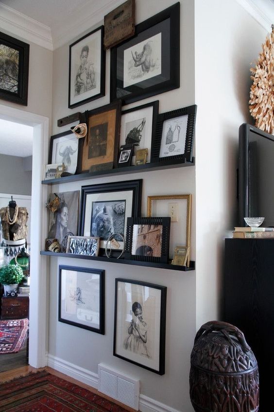 an awkward nook with black ledges and various colored and black and white art in black frames and some more art hanging over the ledges