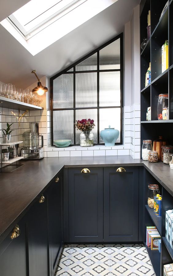 An elegant black U shaped kitchen with butcherblock countertops and a white tile backsplash is chic