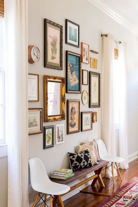 an elegant gallery wall with mismatching gold and dark frames, with a clock and pretty paintings is wow