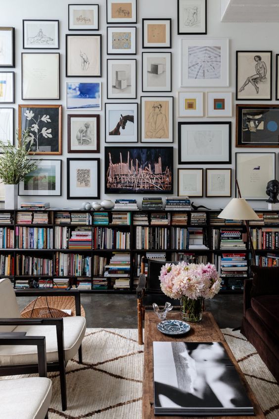 an oversized gallery wall that takes the whole wall and shows off mismatching artworks and frames is all chic