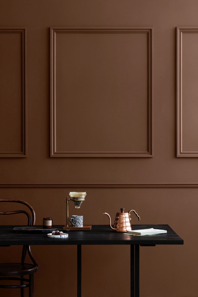 a vintage minimalist space with chocolate brown paneled walls, dark and black furniture is a lovely way to introduce some color