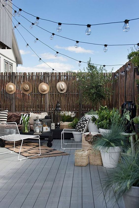 03 a backyard deck styled with string lights over the space and some candle lanterns on the deck is very welcoming and chic