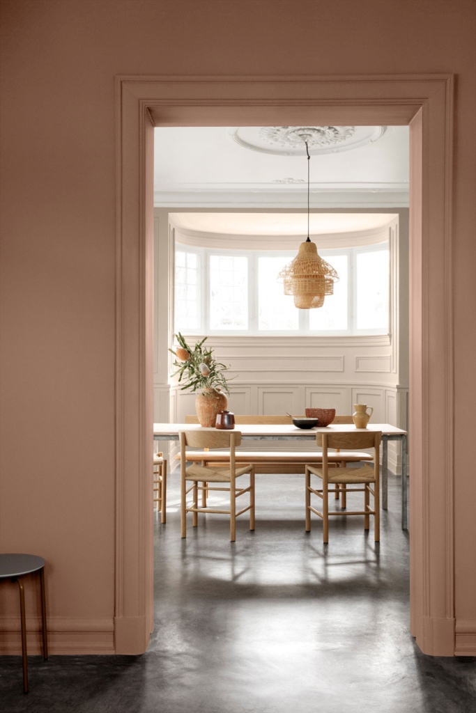 a chic minimal space with a blush wall and doorway to frame a view of the dining space