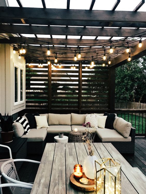 a modern backyard with stylish furniture, string lights over the space and some candles and lights right on the table