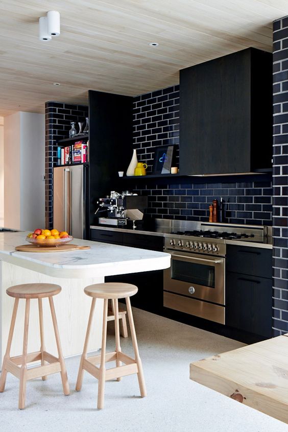 a chic modern black kitchen with a matching hood, a navy subway tile backsplash, metal countertops is stylish and bold