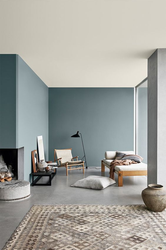 a minimalist living room with pale blue walls and a built-in fireplace, chic furniture and touches of black for drama