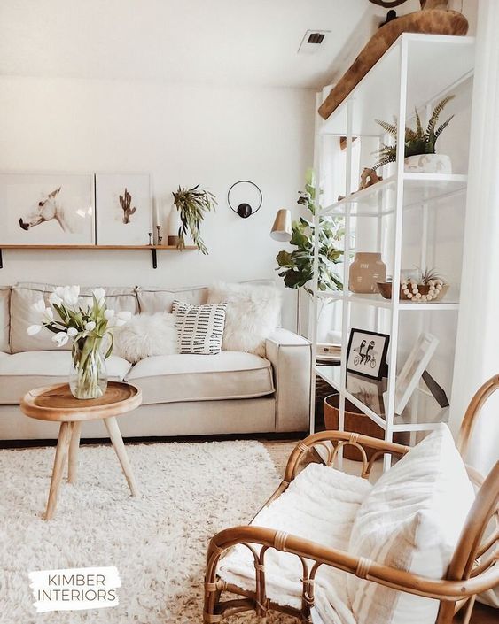 a neutral and cozy living room with a rattan chair, a neutral sofa, a large storage unit and lots of potted greenery