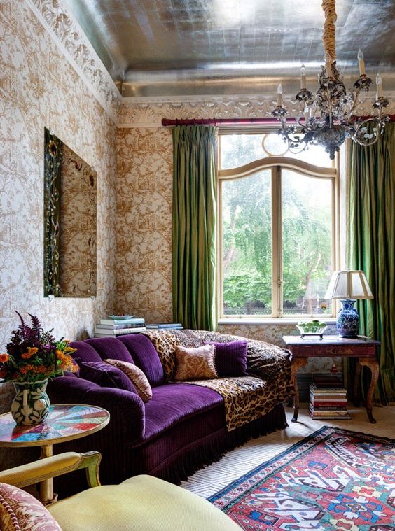 08 a sophisticated vintage living room with printed wallpaper, a purple sofa, a lovely chandelier, green curtais and a printed rug