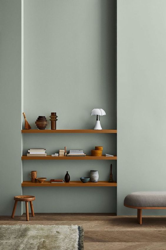 A minimalist space with slate blue walls, built in shelves and stained and grey furniture is chic and cool