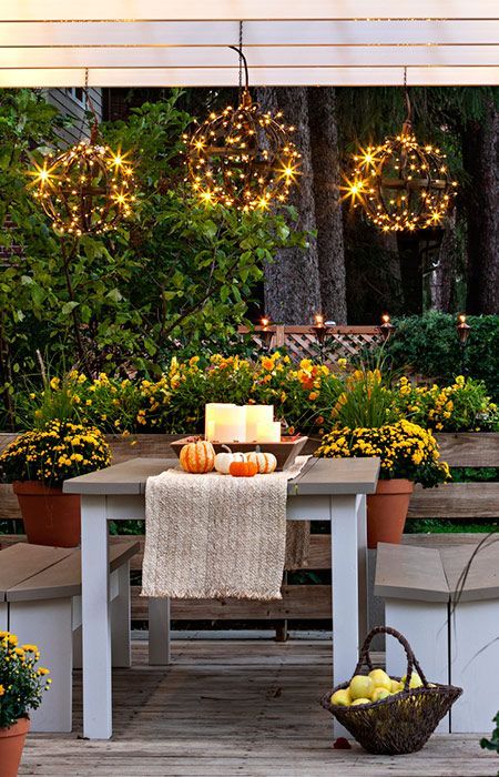 10 a bright fall deck with stylish and simple furniture, potted blooms, candles in a bowl for a centerpiece and light spheres over the table