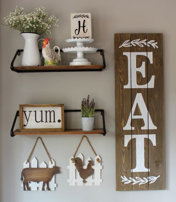 kitchen wall decor wiht a rustic sign, a frame one, plaques with animal silhouettes and potted plants and blooms