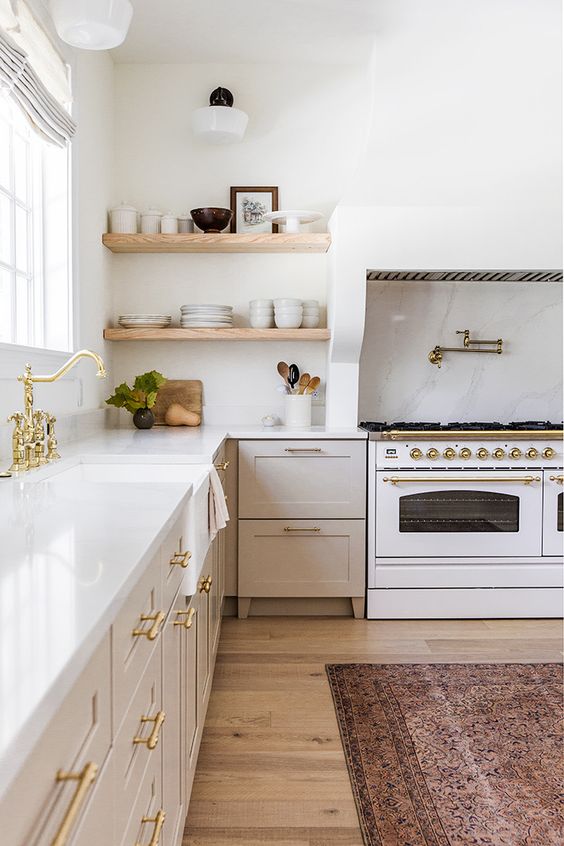 A chic neutral kitchen with gold fixtures and handles, built in shelves and cookers is a beautiful space