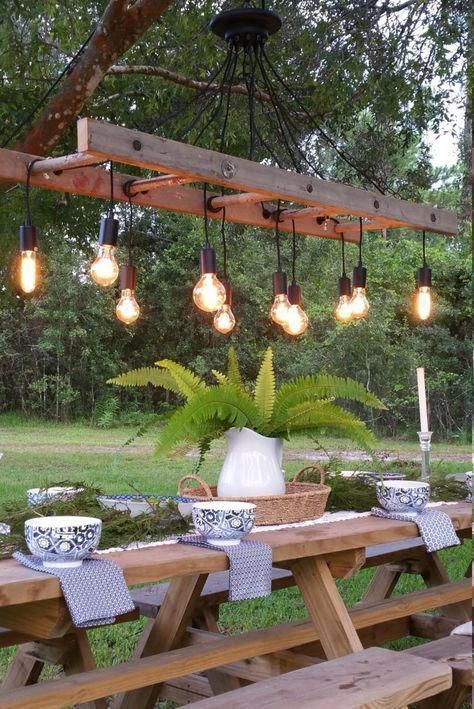 a quirky outdoor dining space with simple wooden furniture and a catchy ladder chandelier with bulbs is wow