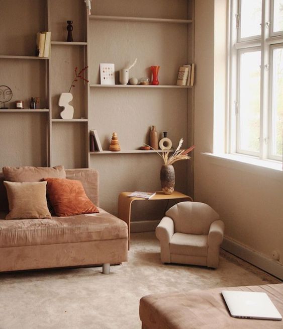 a neutral earthy-toned living room with greige walls, taupe and neutral furniture, built-in shelves and much natural light