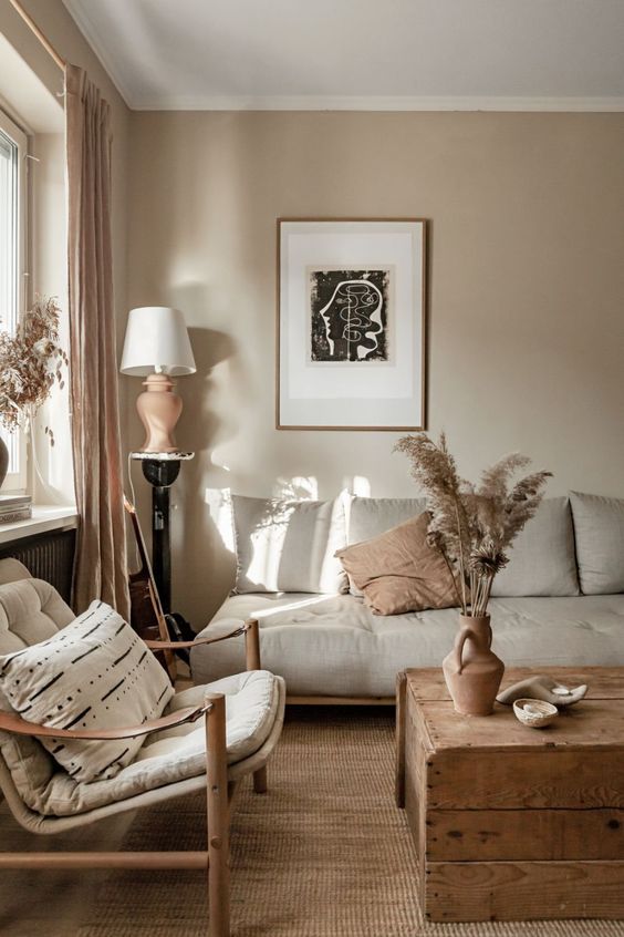a lovely eclectic living room with grey walls, grey seating furniture, a wooden chest as a coffee table, warm touches